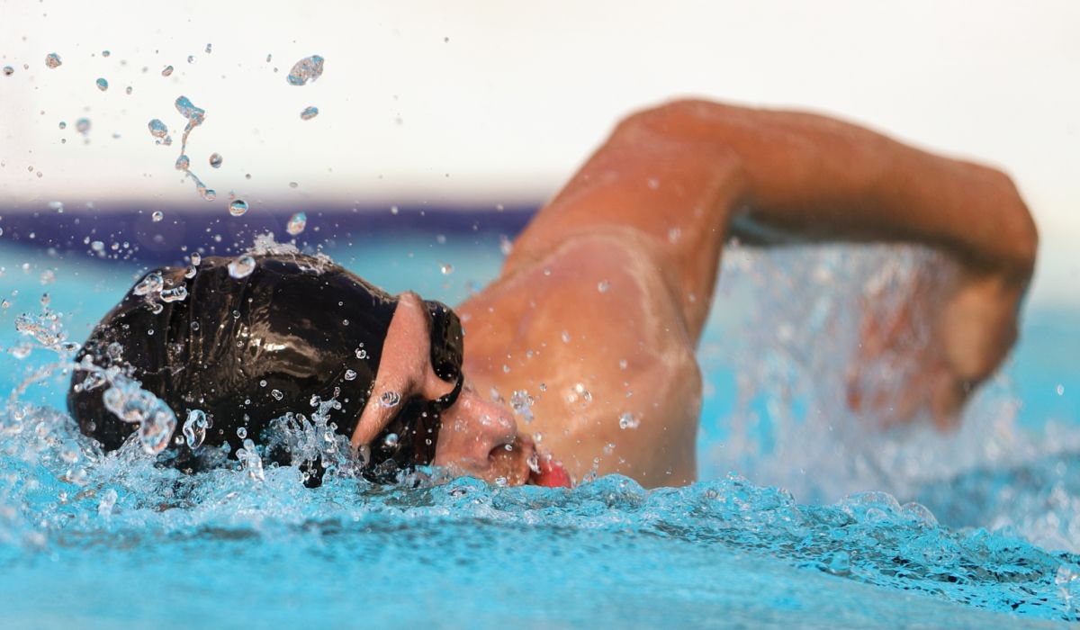 Sport et santé bucco-dentaire : homme nageant le crawl dans une piscine